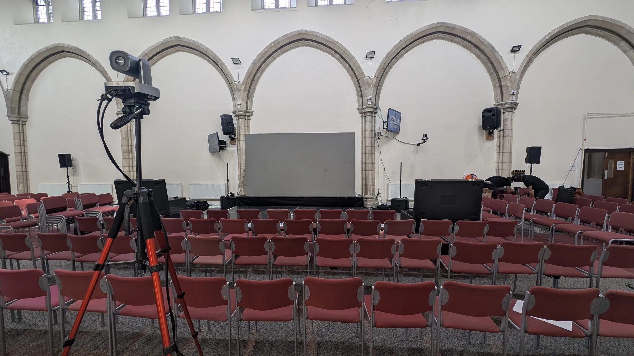 The hall at Full Gospel Revival Centre before the event, with rows of chairs facing the stage and screen, and the PA and relay speakers in place.